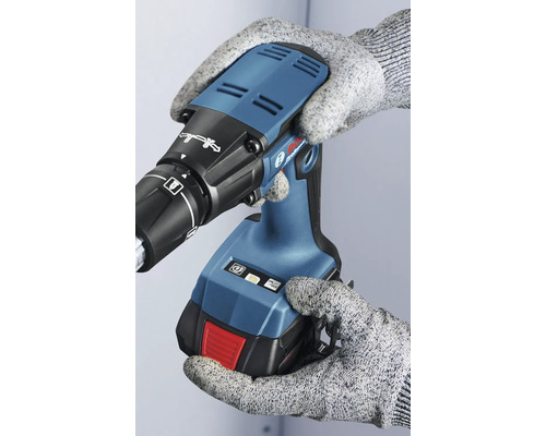 En person med handskar håller i en batteridriven gipsskruvdragare.