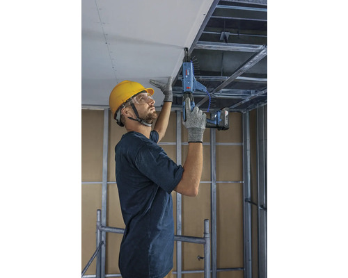 Hantverkare fäster takplattor med en skruvdragare med magasin