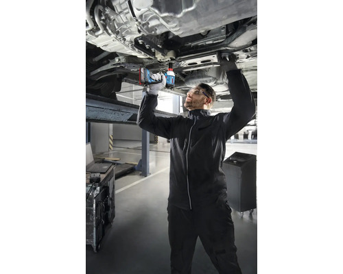 En mekaniker arbetar med en sladdlös mutterdragare på en bil på en billyft.