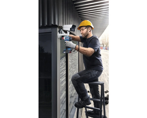 En hantverkare monterar en övervakningskamera med en sladdlös skruvdragare på en stege.