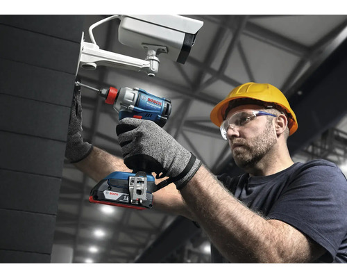 En man med skyddsglasögon och hjälm fäster en övervakningskamera med en batteridriven mutterdragare från Bosch.