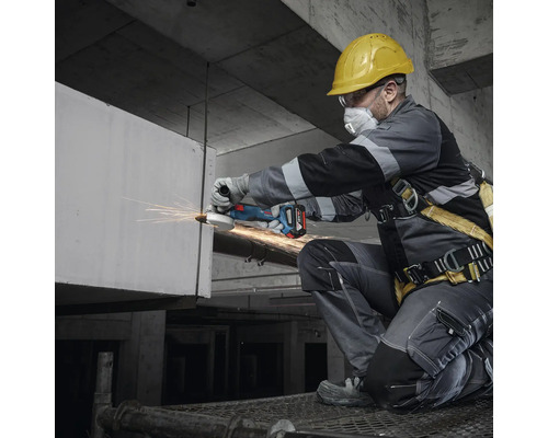 Hantverkare med skyddshjälm, skyddsglasögon och andningsskydd som arbetar med en sladdlös vinkelslip.