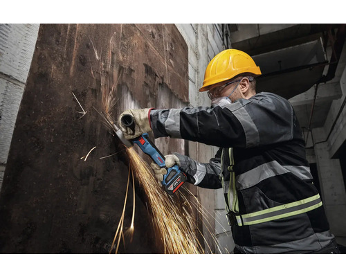 Arbetare som skär metall med en batteridriven vinkelslip