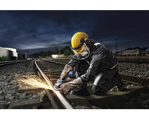 En arbetare slipar en järnvägsräls med en vinkelslip och genererar gnistor.