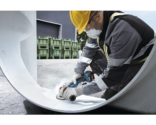 En byggnadsarbetare bearbetar ett rör med en vinkelslip