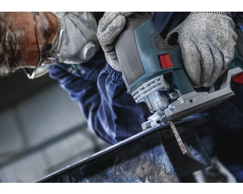 Man skär metall med en sticksåg. Han bär skyddsglasögon, andningsmask och handskar.