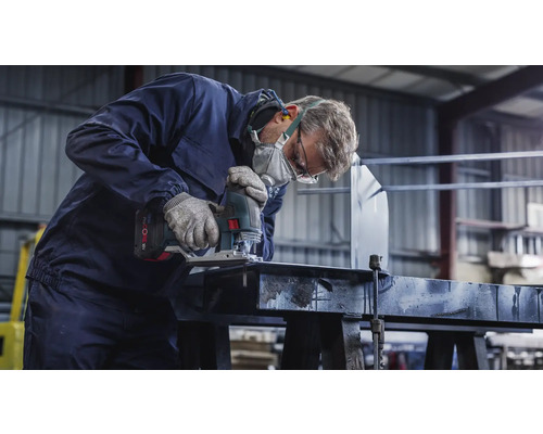 Hantverkare med skyddsmask och skyddsglasögon sågar ett arbetsstycke med en sticksåg.