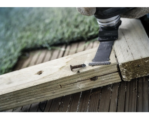 Oscillerande elverktyg skär en spik i en träplanka.