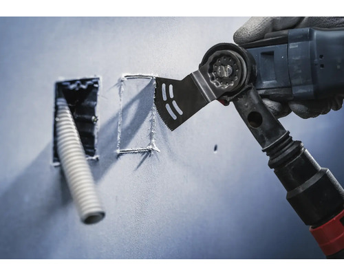 Multifunktionsverktyg skär en öppning i en vägg för ett tomt rör