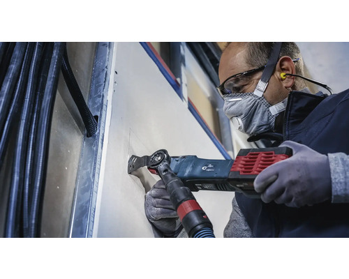 Hantverkare skär en öppning i en gipsskiva med ett multifunktionsverktyg.