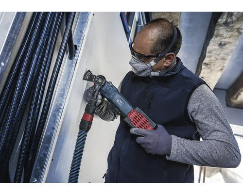 En hantverkare använder ett multifunktionsverktyg för att skära i en vägg