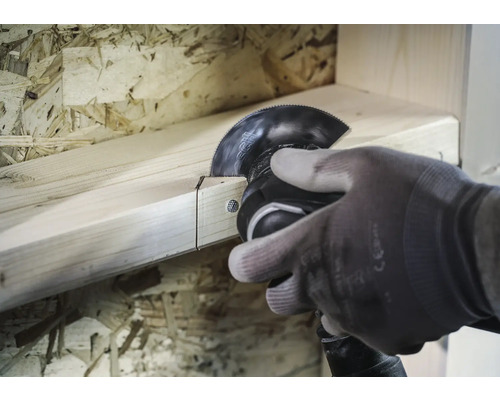 En person sågar en träplanka med ett multifunktionsverktyg.