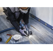 Hantverkare använder multifunktionsverktyg på laminatgolv för renovering.