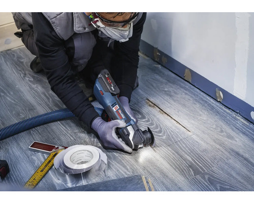 Hantverkare använder multifunktionsverktyg på laminatgolv för renovering.