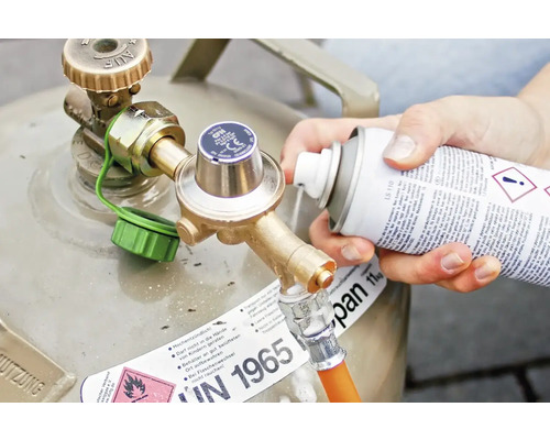 Gasflaska med tryckregulator och person som använder en spray