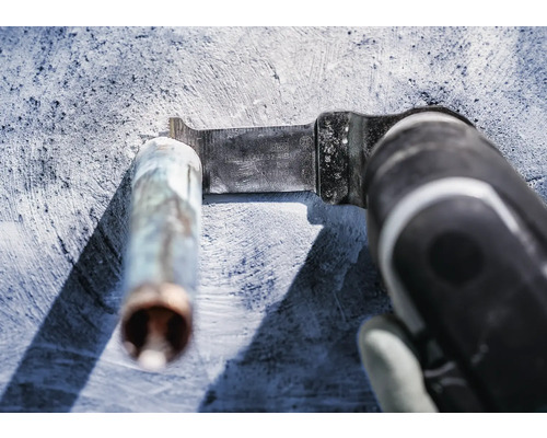 Oscillerande elverktyg med metallsågblad som skär av ett metallrör.