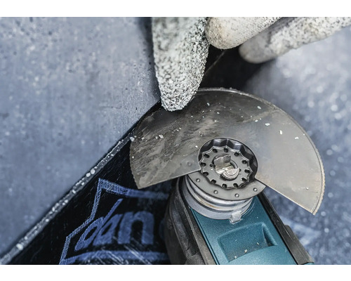 Närbild av en person med skyddshandskar som bearbetar en platta med en vinkelslip.