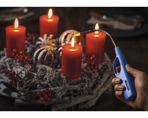 Adventskrans med fyra brinnande ljus och en stavtändare i en hand