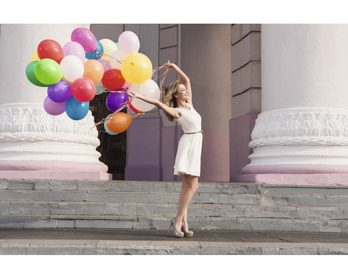 Kvinna med många ballonger framför en byggnad