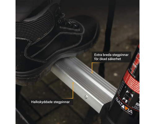 Detaljbild av ett trappsteg med breda halkskyddade stegpinnar och en fot i en arbetssko