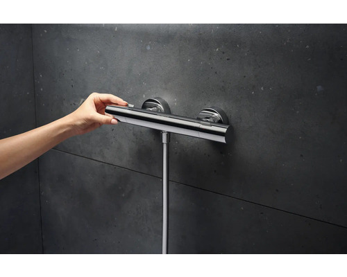 Duschtermostat för utanpåliggande montering med manuell manövrering framför en mörk vägg