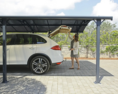 Kvinna öppnar bakluckan på en bil under en carport för skydd mot väder och vind.