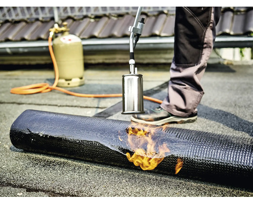 Takläggare svetsar bitumenmembran med en brännare och gasflaska.