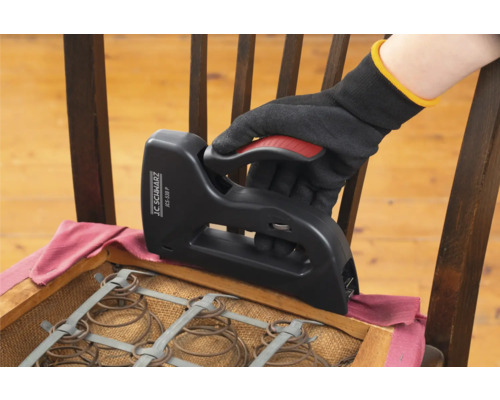 En hand med handske använder en häftapparat för att klä om en stol.