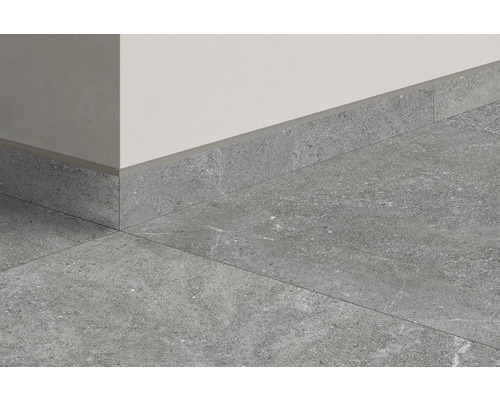 Grå golvplattor och golvlister mot en vägg