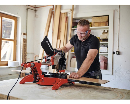 Man med skyddsglasögon arbetar med en Einhell kap- och gersåg i en verkstad.