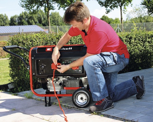 En man ansluter en strömkabel till en Einhell strömgenerator.