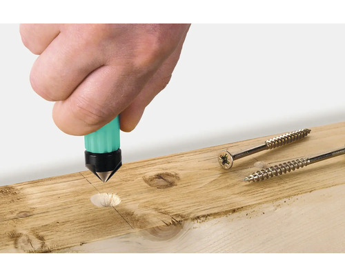 En hand använder en stans på en träplanka bredvid två skruvar.