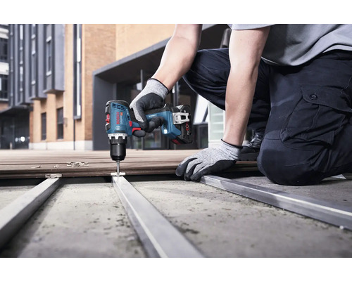 En person använder en batteridriven skruvdragare för att skruva fast ett metallelement.