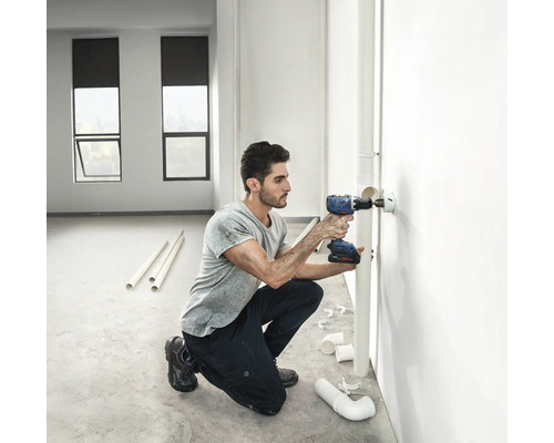 Hantverkare borrar hål med sladdlös skruvdragare i väggen för rörinstallation