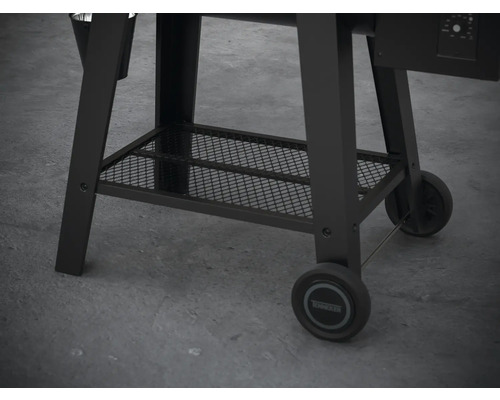 Detaljvy av underredet på en svart pelletgrill med förvaringsutrymme och hjul