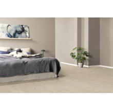 Sovrum med säng, tavla och krukväxt på ljust trägolv