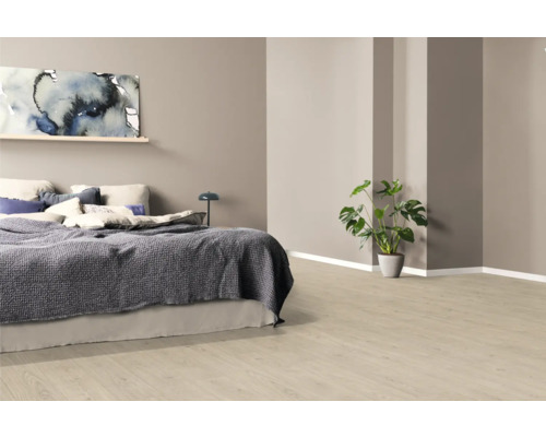 Sovrum med säng, tavla och krukväxt på ljust trägolv