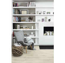 Ljust vardagsrum med bokhylla, fåtölj, repstol och öppen spis