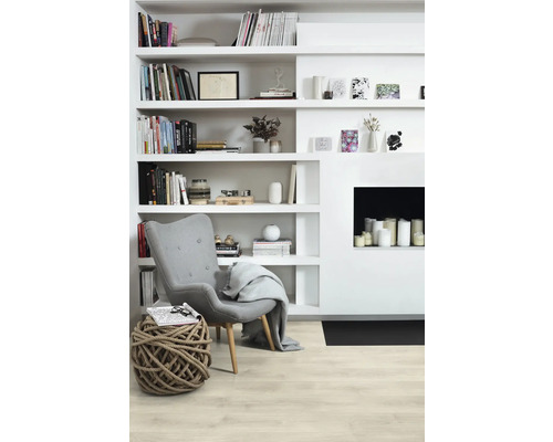 Ljust vardagsrum med bokhylla, fåtölj, repstol och öppen spis