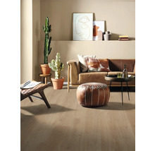 Ljust vardagsrum med soffa, kuddar, växter och trägolv