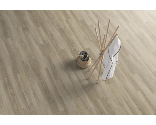 Ljus planka av vinylgolv med träutseende, klädhängare och tvättkorg.