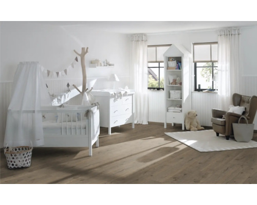 Ljust barnrum med spjälsäng, skötbord, hylla och fåtölj