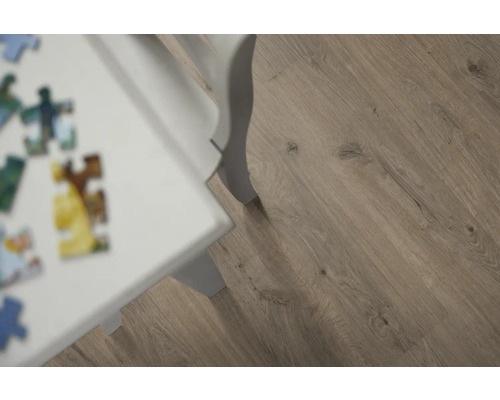 Närbild av laminatgolv med träutseende och vitt bordsben