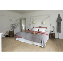 Ljust sovrum med dubbelsäng, nattduksbord och trägolv