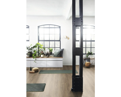 Ljust rum med gymnastikmattor, fönsterparti, växter och en dekorativ stödpelare