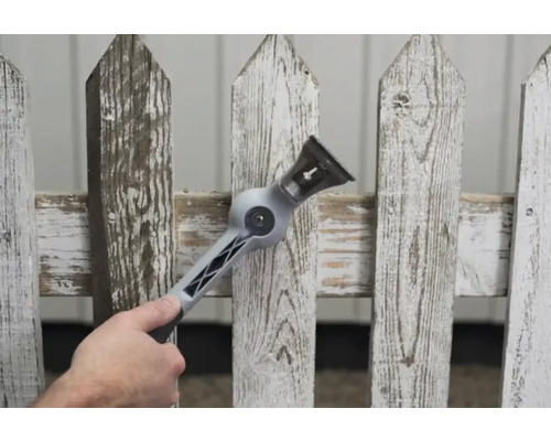 En man använder ett verktyg för att rengöra ett trästaket