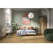 Ljust sovrum med säng, sängbord, lampa, garderob och fåtölj