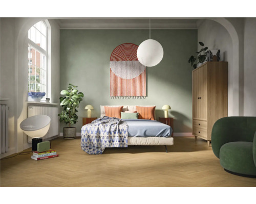 Ljust sovrum med säng, sängbord, lampa, garderob och fåtölj