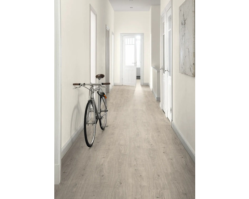 Hall med ljust laminatgolv, vita väggar och en cykel