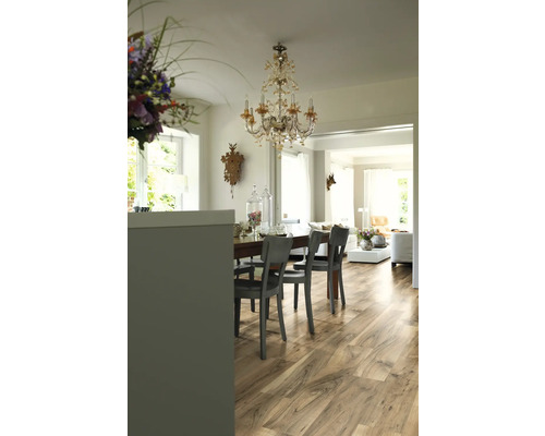 Matsal med trägolv, matbord, stolar och kristallkrona